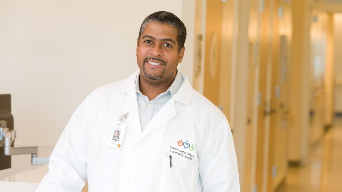 Smiling portrait of Dr. Fisher, a middle-aged black man, in MLKCH hospital hallway