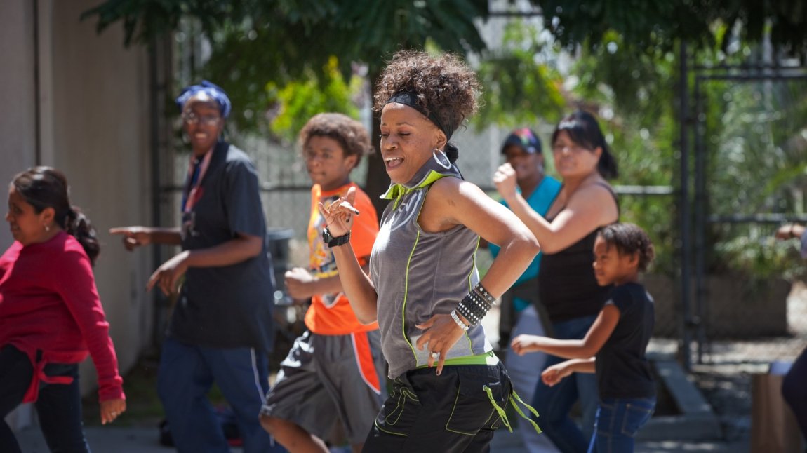 Black woman leads a group of dancers outdoors