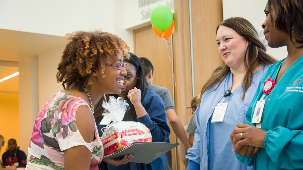 Black female patient talks to two nurses in blue scrubs at event