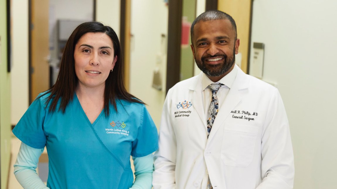 Latina nurse and black male doctor smiling in clinic hallway