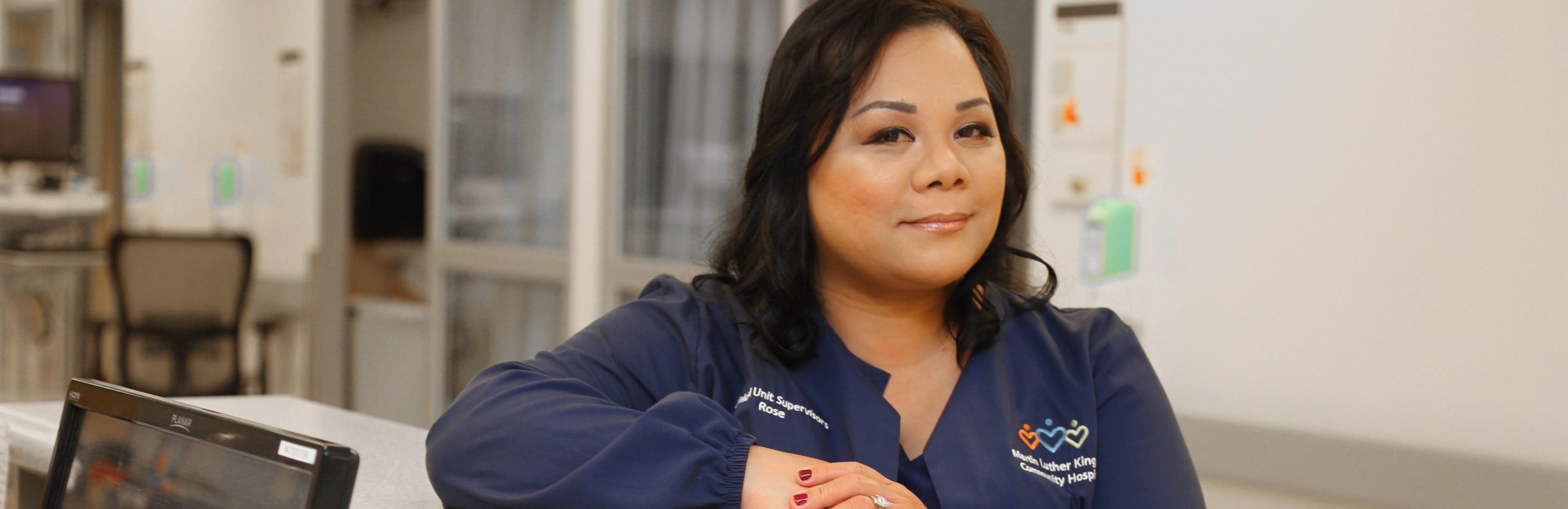 Smiling ICU Nursing Supervisor Lyrose Ortiz standing at nurse’s station