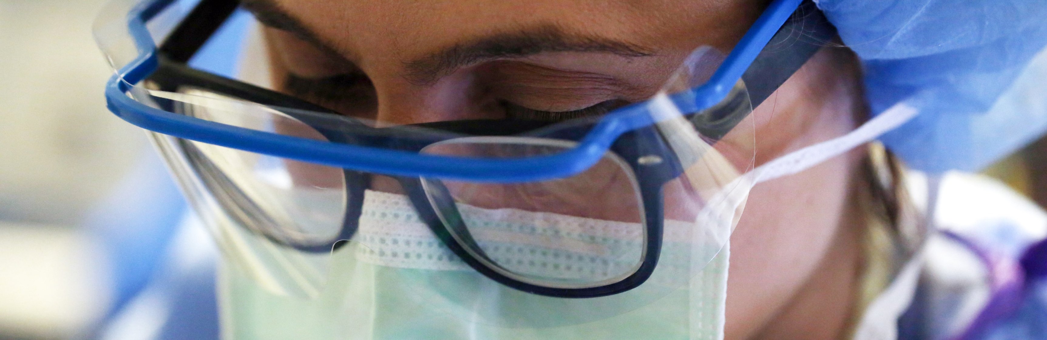 Closeup of a surgical nurse wearing glasses, face shield, and mask 