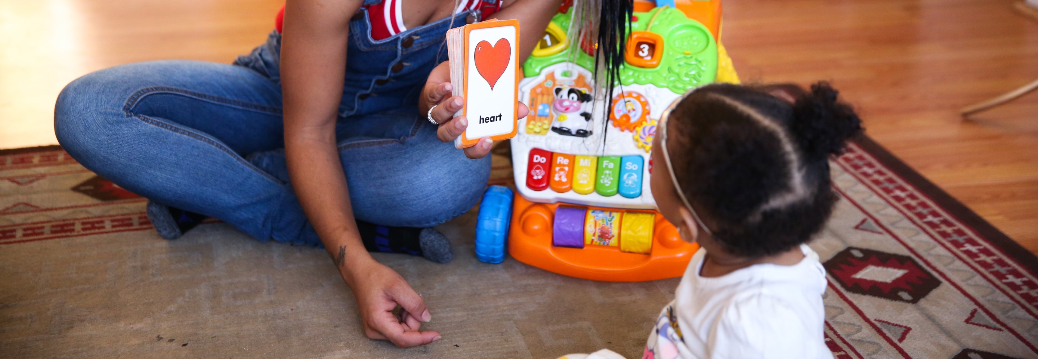 Close up of Black mother showing her baby a flash card that reads heart