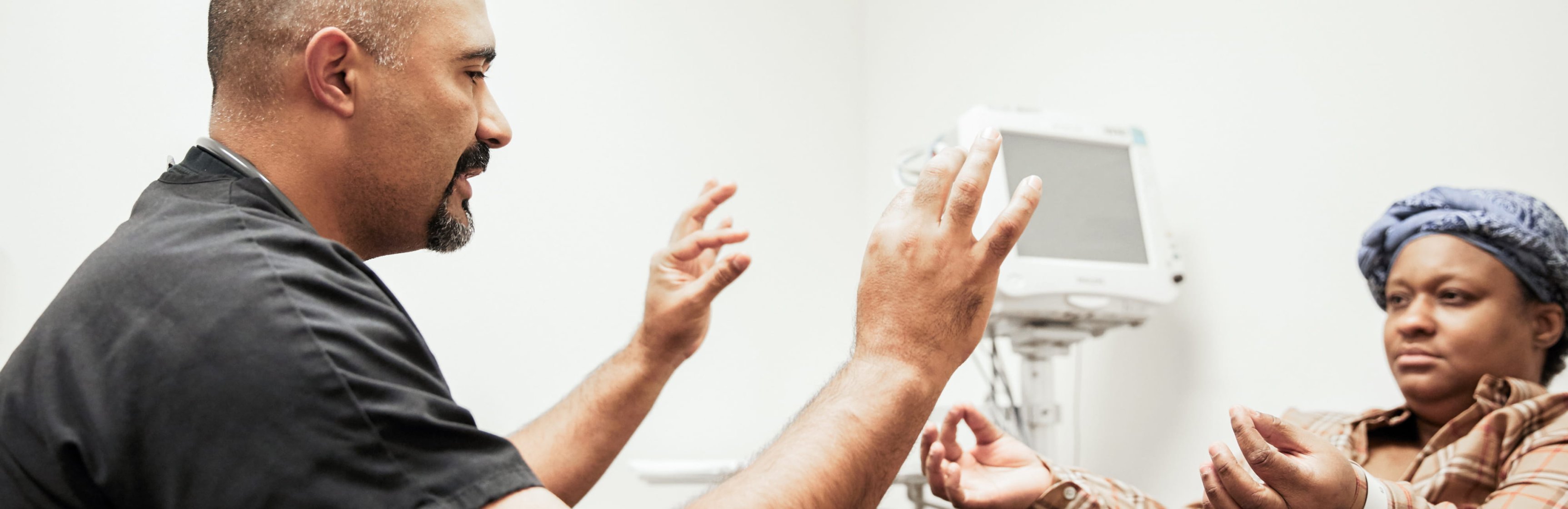 Male Latino doctor making hand gestures, mirrored by Black female patient