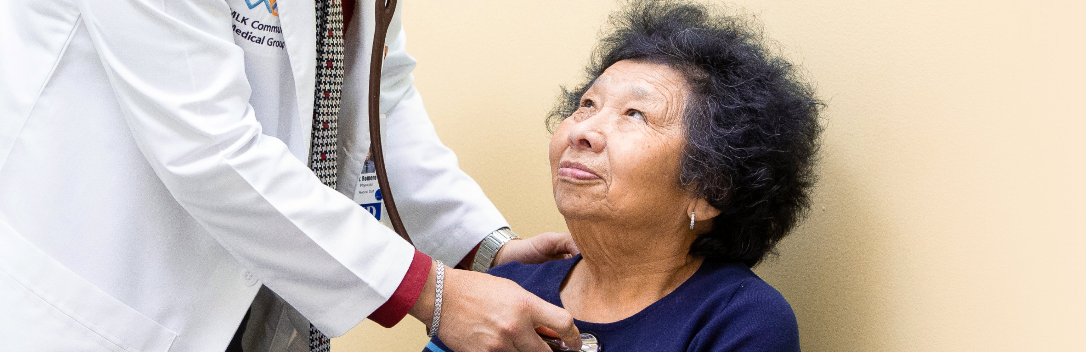 Older Latina patient looking up at doctor in white coat