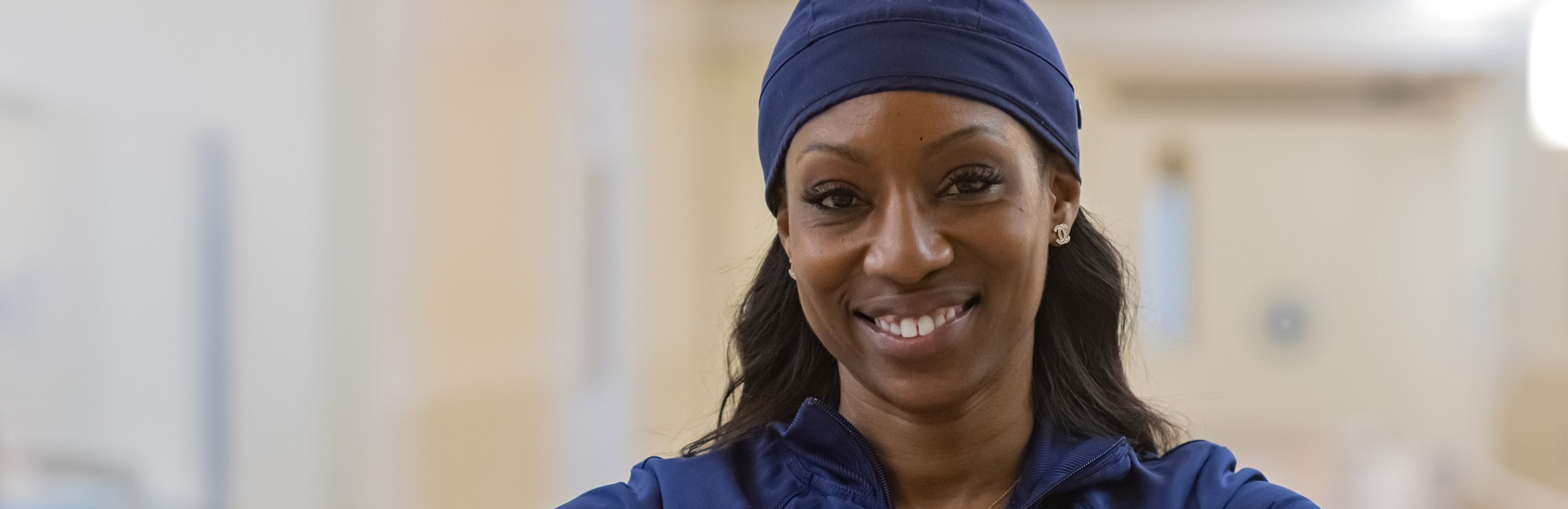 Photo of a nurse smiling, wearing a head wrap