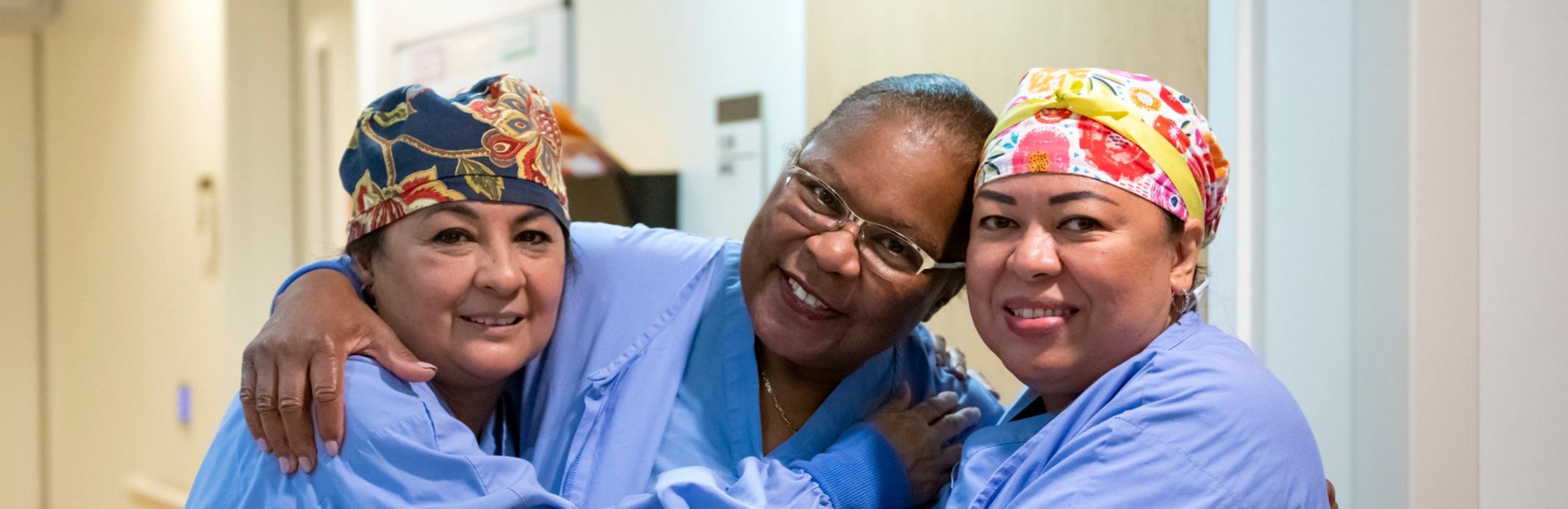 Photo of three diverse female nurses hugging