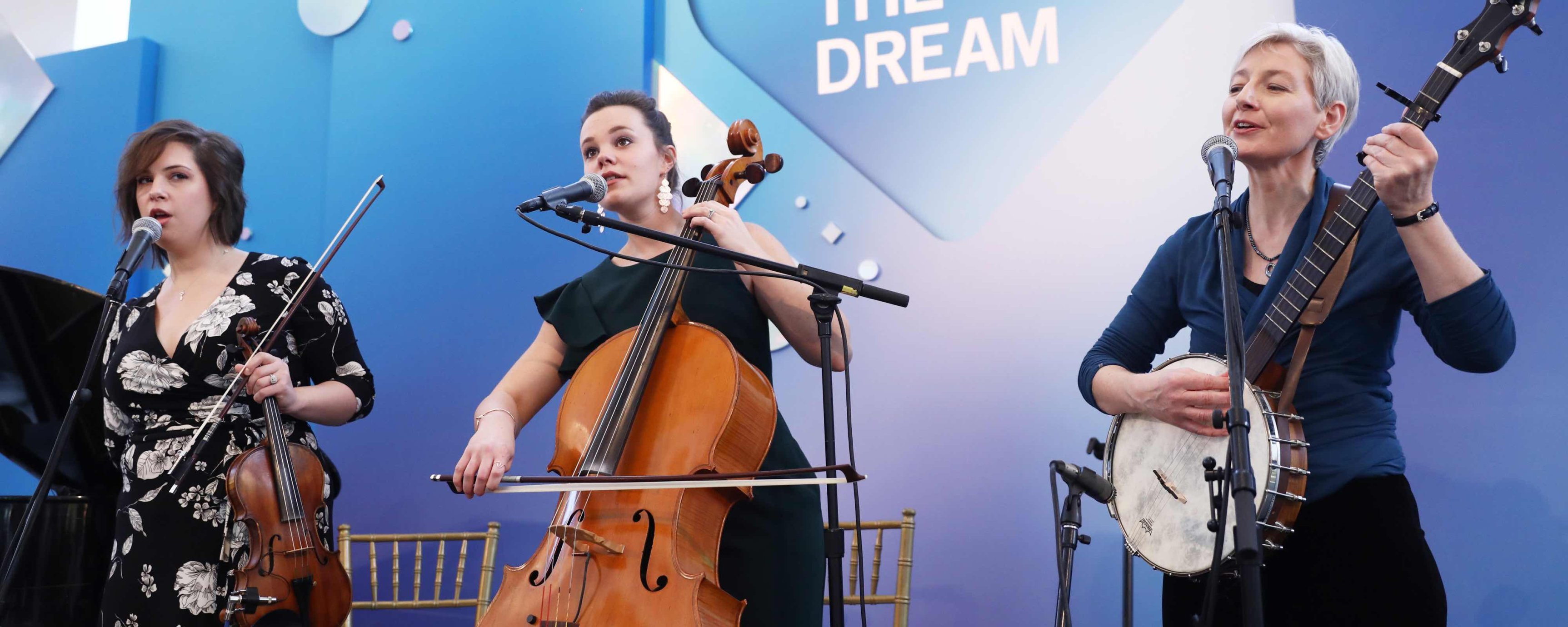 Three white female musicians playing cello, banjo and violin on the Dream Lunch stage