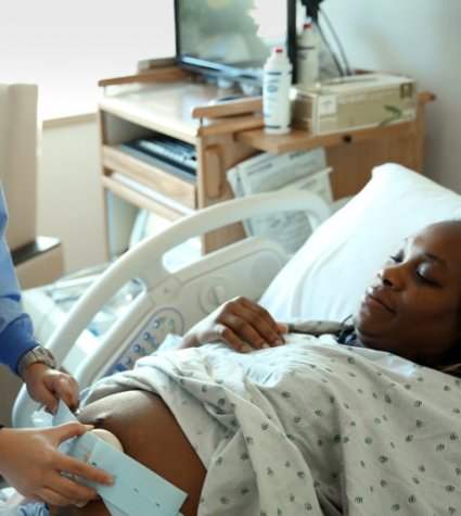 A nurse puts a fetal monitor on a pregnant mother’s belly