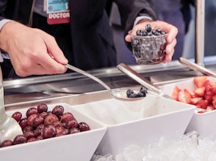 Close up of hands scooping blueberries at a salad bar