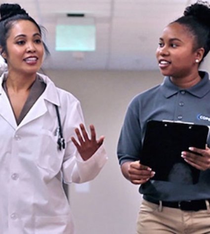 Young Black female doctor walking down hall speaking with young Black COPE scholar