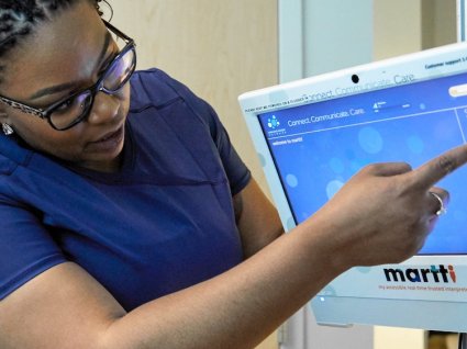 Black female nurse pointing at screen of interpretation machine