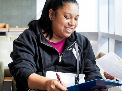 Close up of Latina woman smiling and holding clipboard