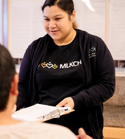 Young female staff member handing clipboard to patient