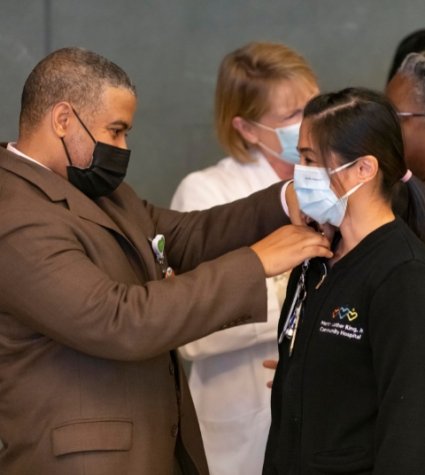 Foto del Dr. Disher colocando un pin a una empleada