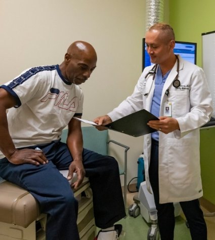 Photo of a male Hispanic physician with a Black patient in a patient room