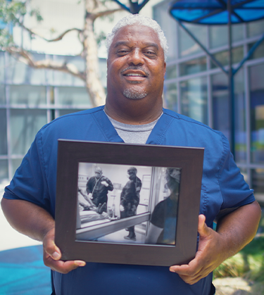 Man holding a photo of himself during COVID