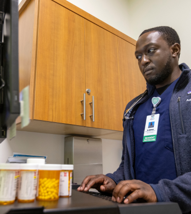 Photo of a resident physician typing on a computer.