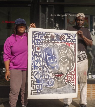 Photo of Aziz & Camille holding a piece of art in front of Aziz Gallerie