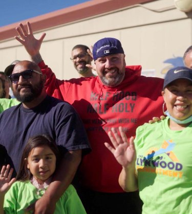 Rev. Rudy Rubio standing with his arms up, surrounded by community members