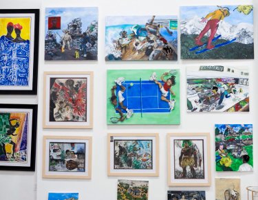 Photo of multiple pieces of Aziz's art hanging on a wall