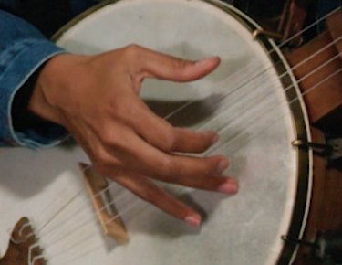 Close up photo of Rhiannon's hand strumming a banjo