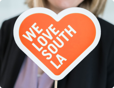 Woman holding sign that says "We love South LA"