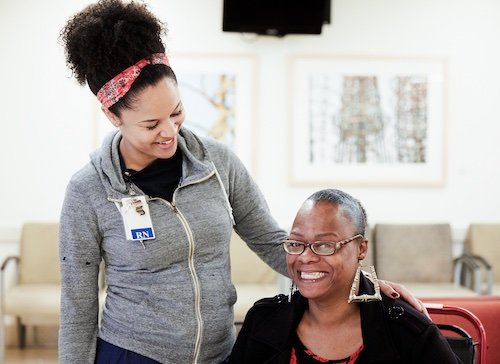 Younger Black woman smiling with hand on shoulder of older Black woman 