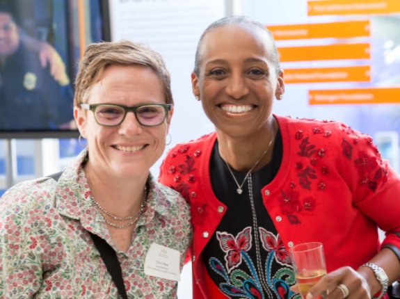 Middle-aged white woman smiling next to middle-aged Black woman at an event