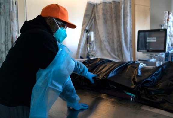 Photo of a masked African American man standing over a body bag