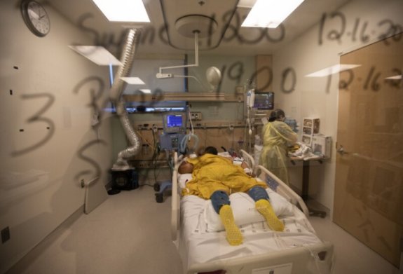 Patient lying in emergency room bed with a nurse tending to him