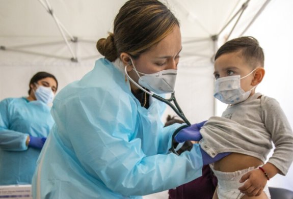 Photo of a nurse checking a child with a stethoscope 