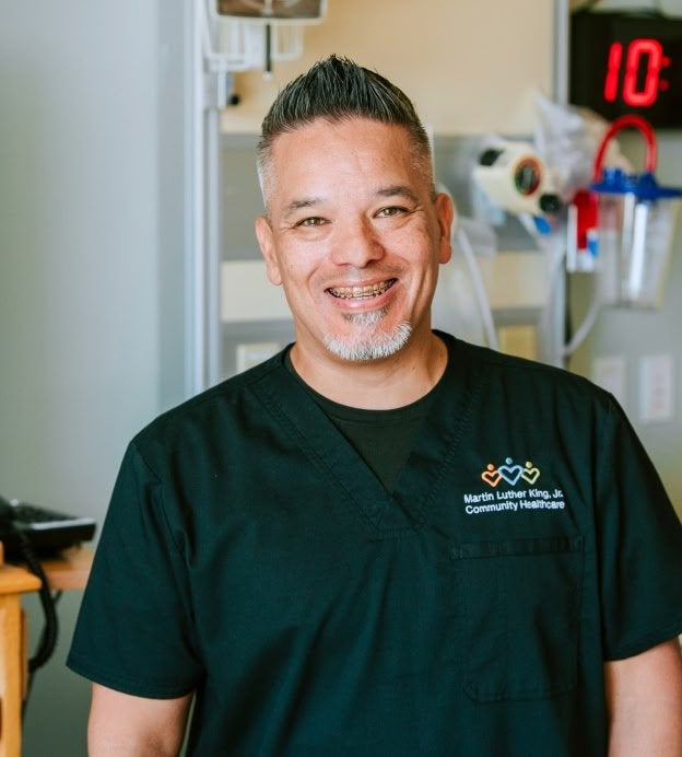 Man smiling in front of hospital equipment