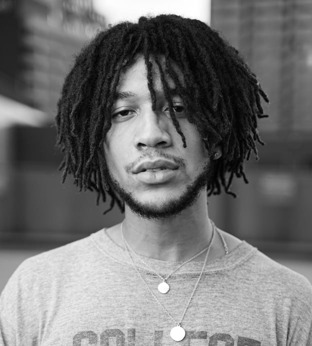 Black and white headshot of Justin "Demeanor" Harrington, a young Black man