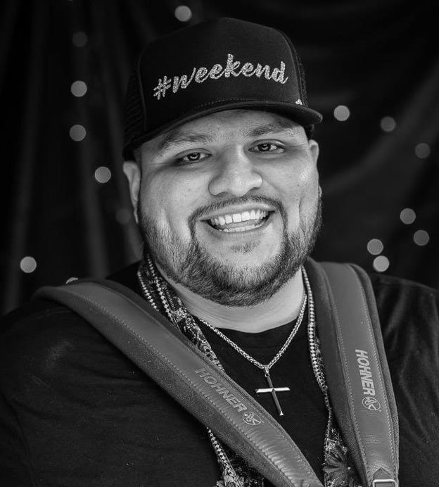 Black and white headshot of Josh Baca, a young Latino man wearing a baseball cap