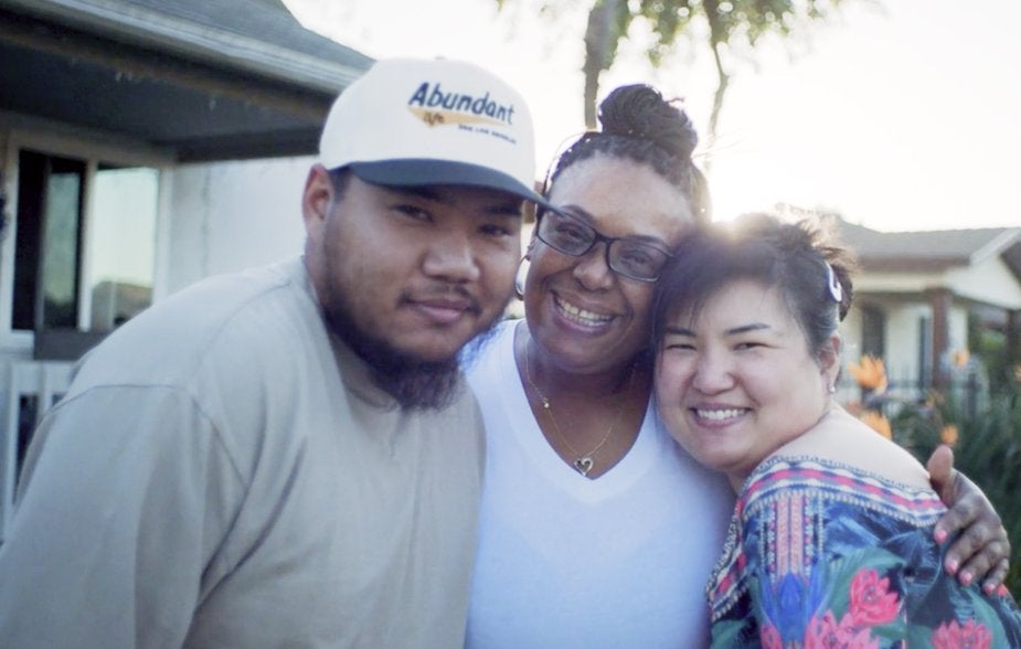 Family hugging in front of their house in South LA