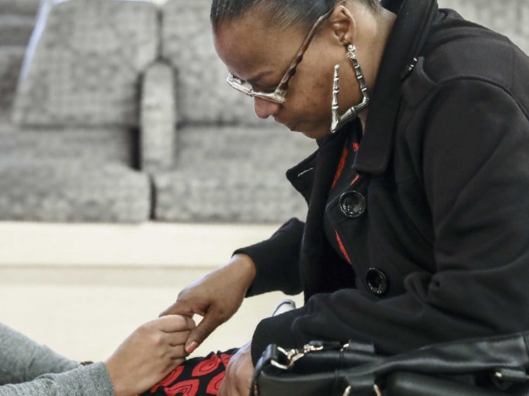 Black woman whose hand is being held by an unseen volunteer