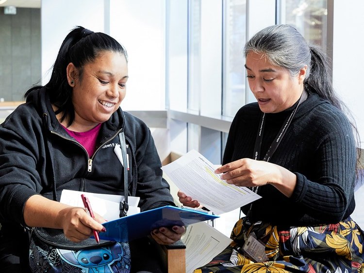 Paciente latina sonriendo y revisando documentación con una administradora latina del hospital