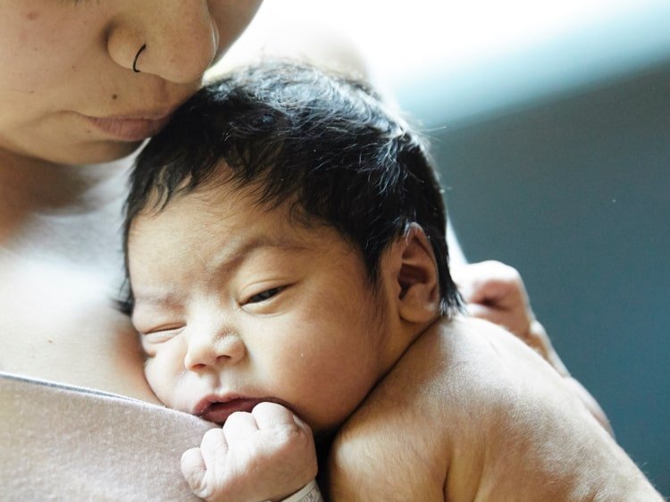 Newborn baby being held against mother's chest