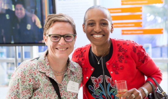 Middle-aged white woman smiling next to middle-aged Black woman at an event
