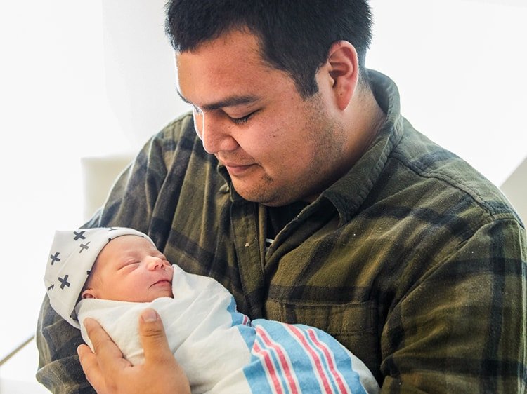 Latino father holding his newborn baby