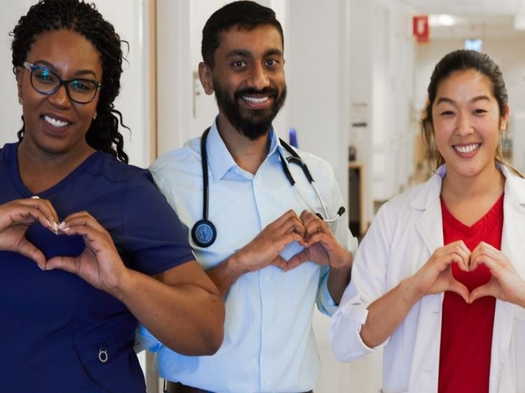 Dos miembros mujeres y un hombre del personal de diferentes razas haciendo corazones con las manos y sonriendo