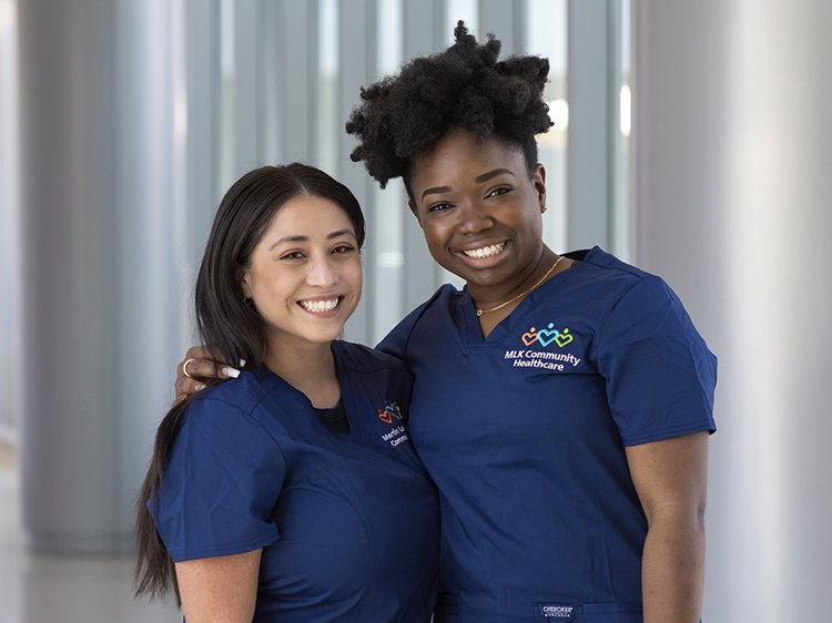 Photo of two nurses smiling (one African-American and one Latin-x)