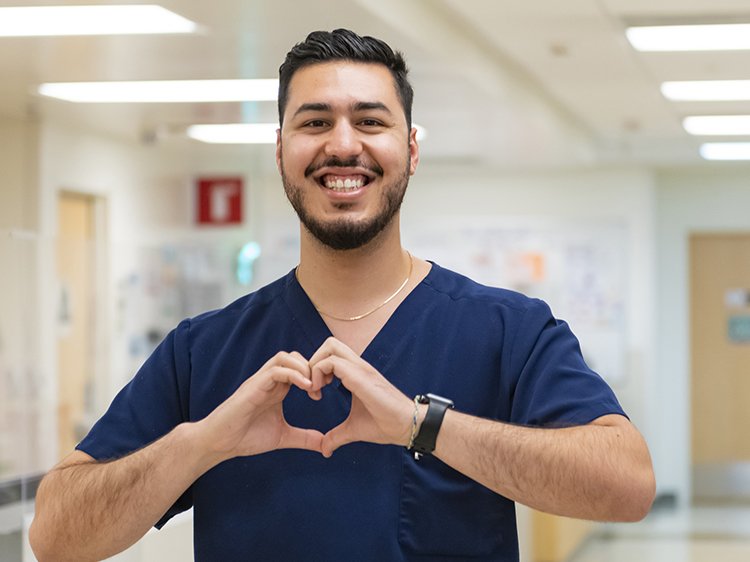 Photo of male nurse smiling and making the heart sign with his hands