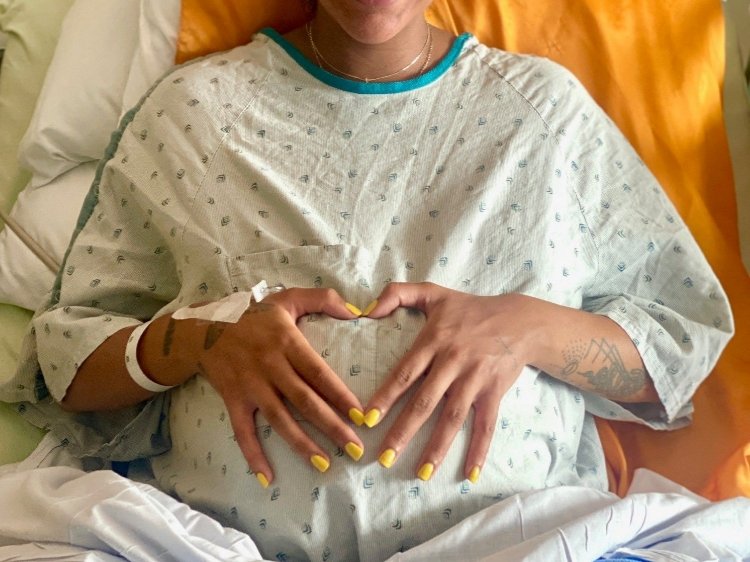 Photo of heart hands over pregnant belly AA
