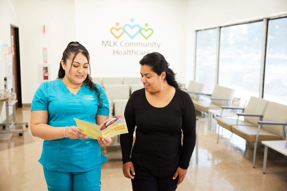 MLKCH employee showing patient educational materials at East Compton clinic.