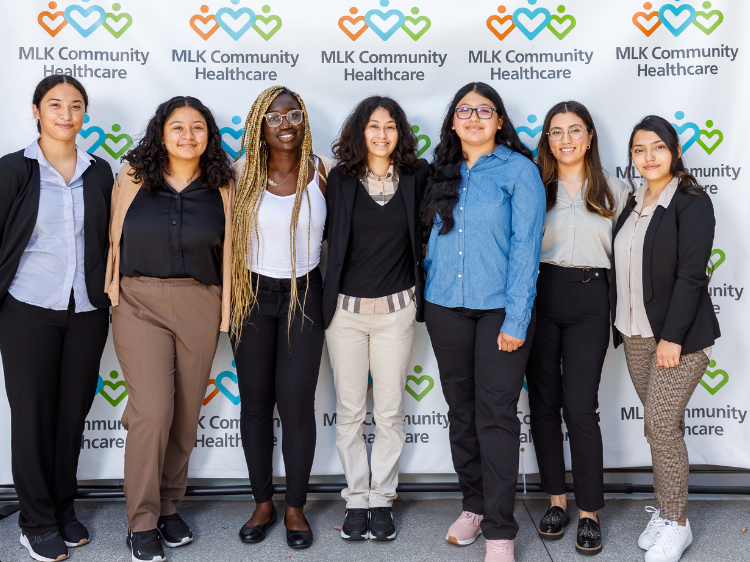 A group of 7 high school students standing in front of an MLKCH step and repeat.